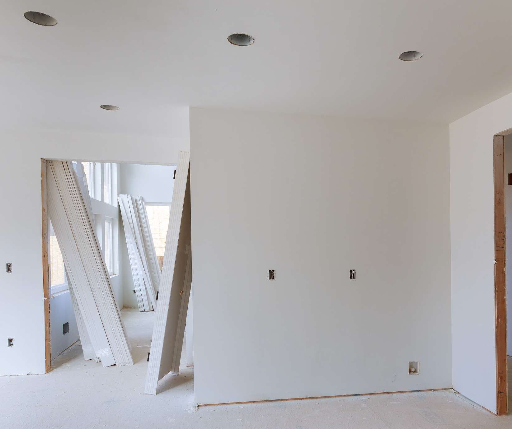 Basement renovation in progress in Tolland County CT with drywall installation, recessed lighting, and white primed doors.